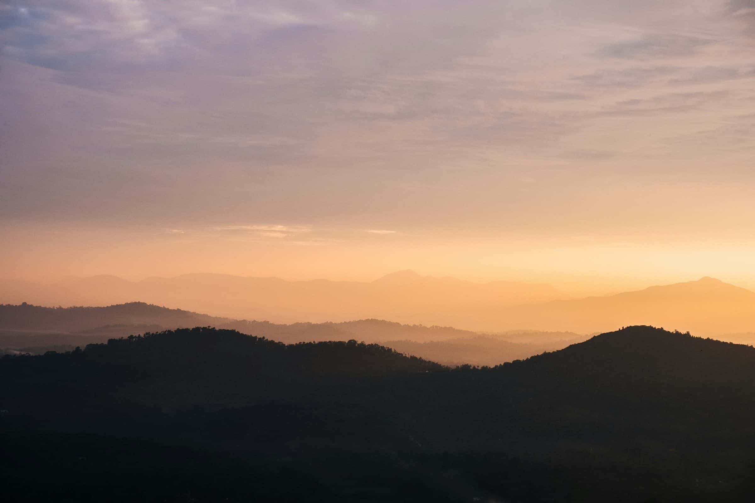 Layered hills in silhouette under a warm evening sky, from Raja's Seat in Madikeri